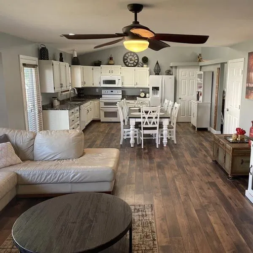 Wood plank flooring running from a living room into an open kitchen and dining area.