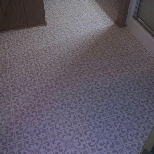 Patterned encaustic look floor tile in a bath beside a shower enclosure.