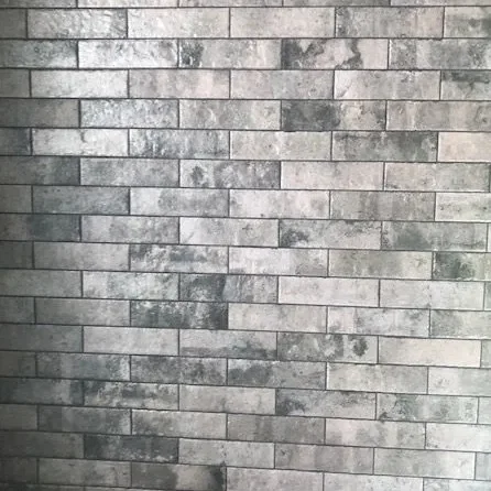 Weathered grey subway tile laid in a running bond pattern on a wall.