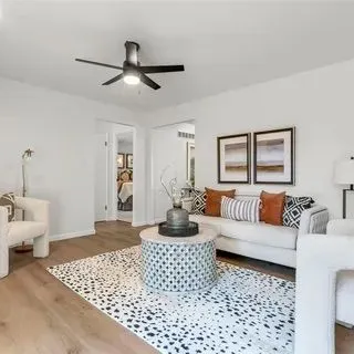 Light oak plank flooring in a living room with a patterned area rug.