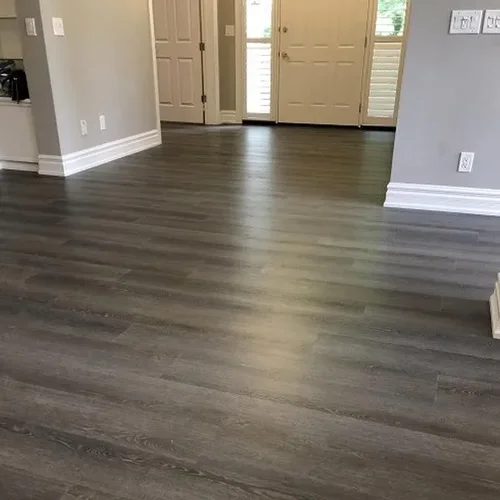 Grey wood look plank flooring running through an open living area toward a front door.
