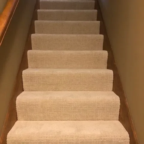 Beige loop carpet fitted to a straight run of stairs.