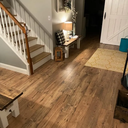 Rustic wood look plank flooring at the foot of a staircase in an entry.