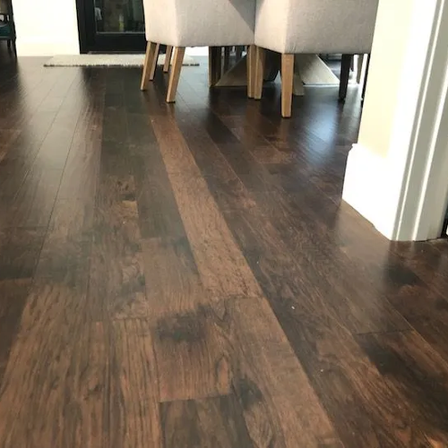 Dark hickory plank flooring in a dining area with upholstered chairs.